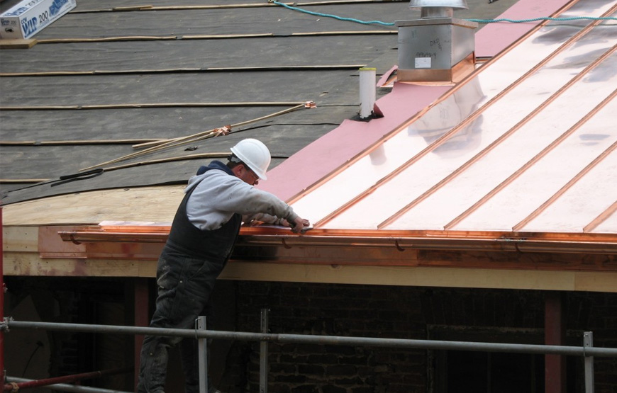 Professional roofer repairing damaged metal roofing panels and flashing